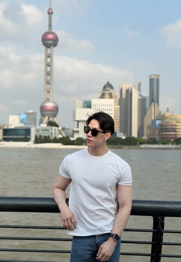 เทรนเนอร์เท็น ในชุดเสื้อยืดสีขาวริมทางเดินชมวิวตึกระฟ้าและหอไข่มุก